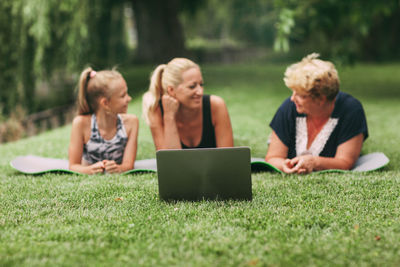 Multi generational family exercising with laptop on grass