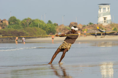 Men at beach against sky