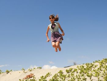 Full length of man jumping against clear sky