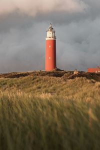Lighthouse on field against sky