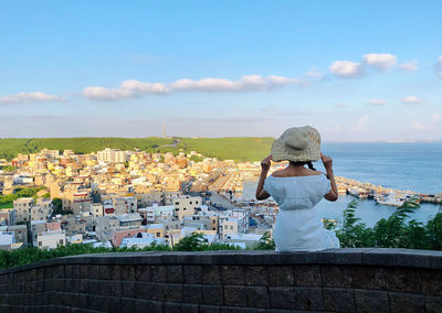 Rear view of woman looking at cityscape against sky