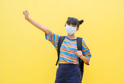 Man with umbrella standing against yellow background