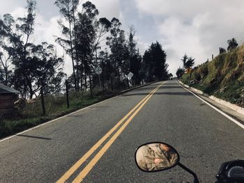 Road by trees against sky