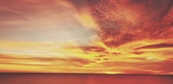 Scenic view of sea against dramatic sky during sunset