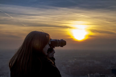 Female photographer against orange sky during sunset