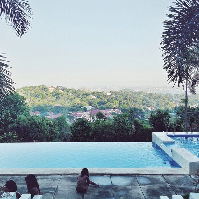 tree, clear sky, water, palm tree, sea, building exterior, built structure, copy space, architecture, growth, swimming pool, tranquil scene, nature, relaxation, tranquility, scenics, sunlight, sky, city