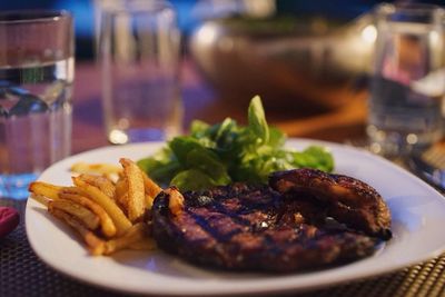 Barbecue steak with french fries and lettuce in plate on table