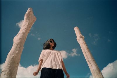 Rear view of woman standing by wooden poles against sky