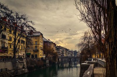 River amidst buildings against sky during sunset