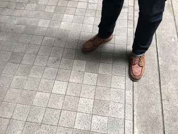 Low section of man walking on tiled floor