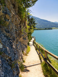 Footpath by lake against sky