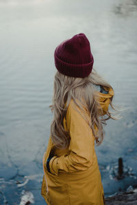 Rear view of woman standing by sea against sky