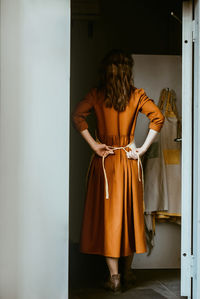 Woman standing at the front door tying an apron person