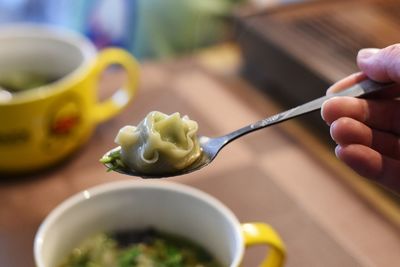 Close-up of hand holding bowl of food on table