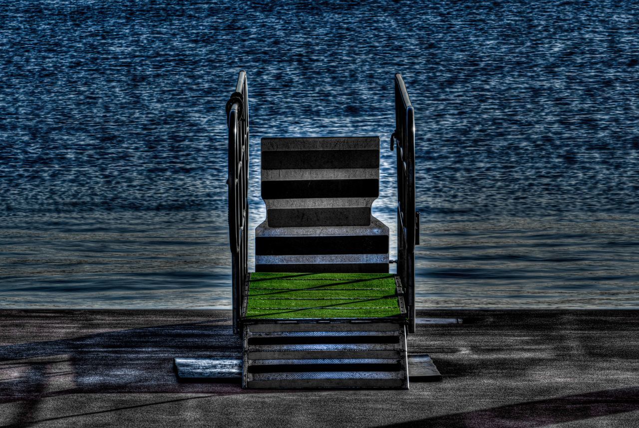 EMPTY CHAIRS BY SEA AGAINST SKY
