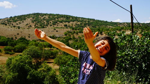 Woman with arms raised on landscape against sky