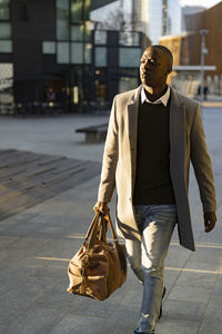 Businessman with duffel bag walking in city