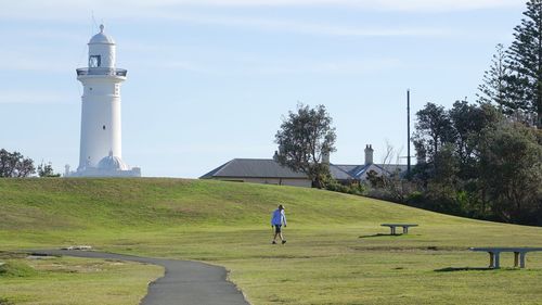 Man by lighthouse against sky