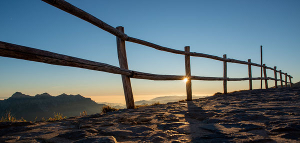 Bridge over snow covered land against clear sky during sunset