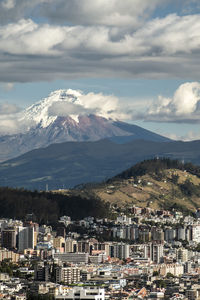 Aerial view of townscape and mountains against sky