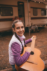 Brown hair teenage girl playing guitar at family camping in forest