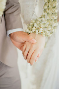 Midsection of bride holding bouquet