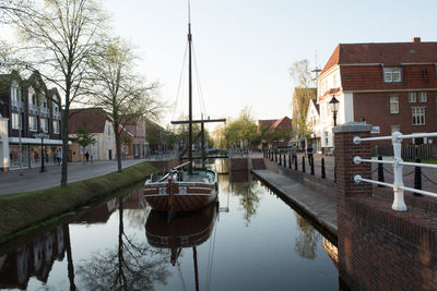 Boats moored in canal by buildings against sky