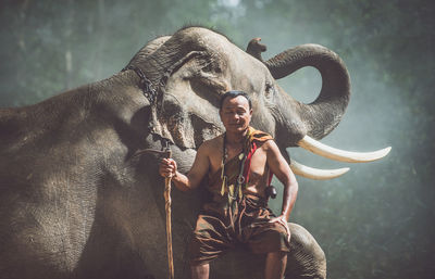Man standing with elephant in forest
