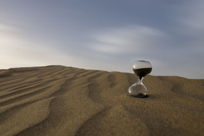 Close-up of umbrella on sand at beach against sky