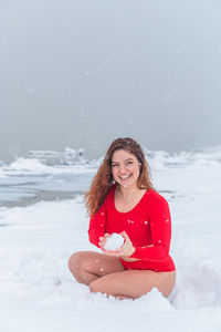 Portrait of smiling woman holding snow during winter
