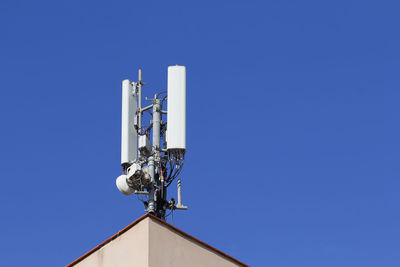 Low angle view of communications tower against clear blue sky