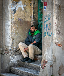 Portrait of young woman sitting against wall