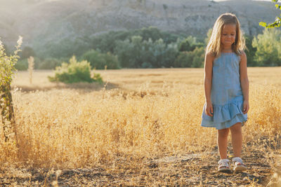 Full length of girl standing on grassy field against mountain