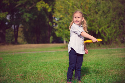 Cute girl holding plastic disc while standing at park