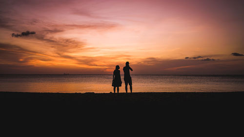 Silhouette of people on beach at sunset