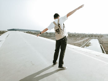 Rear view of man standing on road against sky