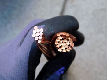 Directly above shot of cropped hand of person holding copper cable 