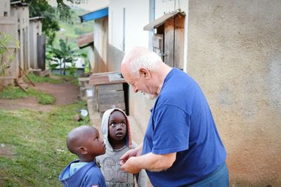 Portrait of father with son against house