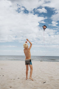 Boy on beach playing with kite