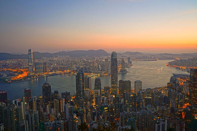 Illuminated cityscape against sky during sunset