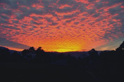 Scenic view of silhouette field against orange sky