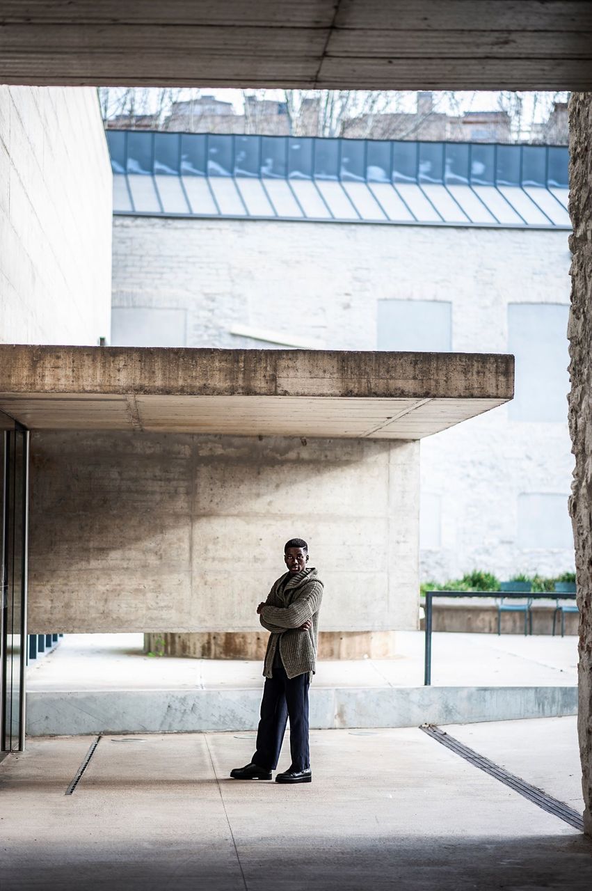 REAR VIEW OF MAN STANDING ON BUILDING