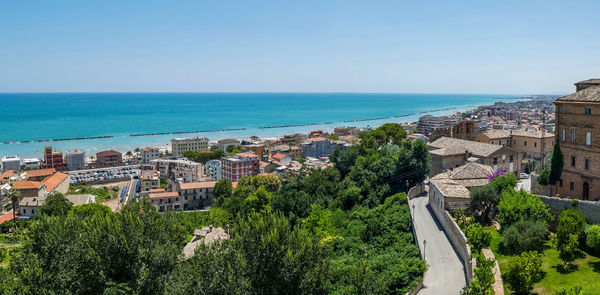 High angle view of townscape by sea against clear sky