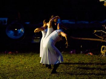 Women standing on field during night