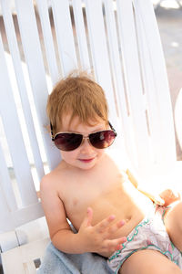 Small child in panama hat plays in the summer on sunny day near swimming pool