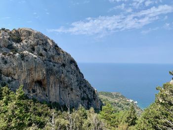 Scenic view of rocks by sea against sky