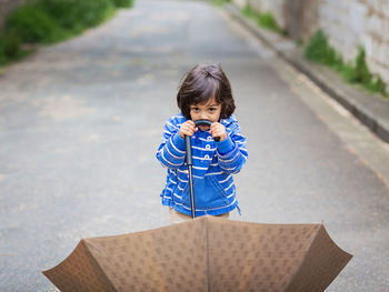 Little handsome baby boy playing with umbrella outdoor