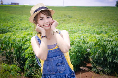 Portrait of smiling woman with hands on chin standing against farm