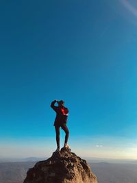 Rear view of women standing on mountain against clear blue sky