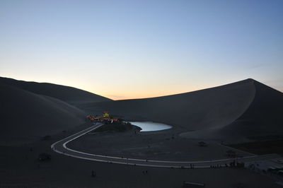 People riding motorcycle on road against sky during sunset